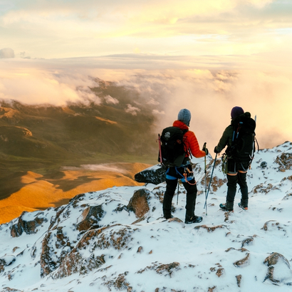 Hikers standing on a snow-covered mountain ridge in Colombia’s Andes overlooking valleys and clouds