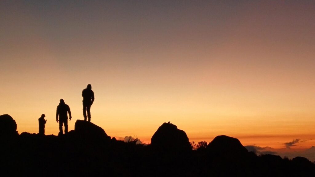 Silhouettes of climbers at Arenales camp on Nevado del Tolima in Colombia against a colorful sunset sky.