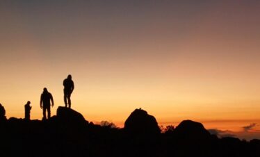 Silhouettes of climbers at Arenales camp on Nevado del Tolima in Colombia against a colorful sunset sky.