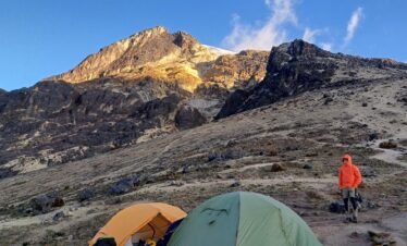 Mountain tents at Arenales camp on Nevado del Tolima in Colombia, with climber and volcanic slopes at sunrise.
