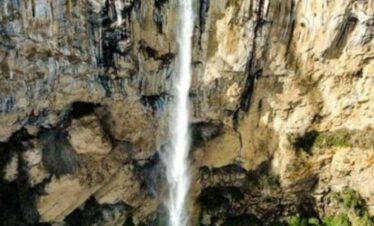Cascada del Salto San Romualdo waterfall dropping from a high cliff into a pool surrounded by lush vegetation in Colombia.