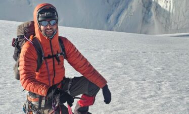 Mountaineer kneeling on glacier with ice axe near a crevasse on Nevado del Tolima.