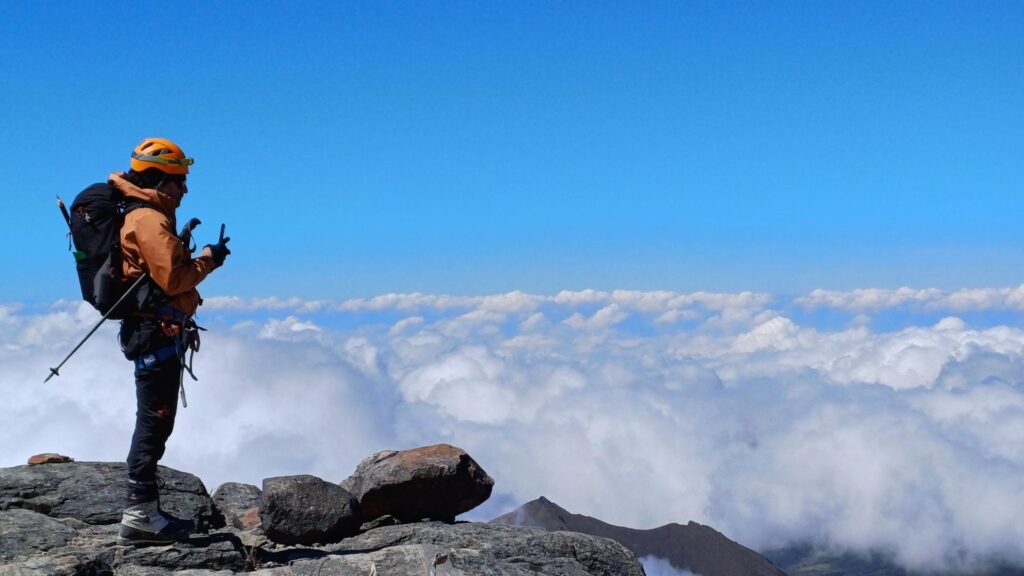 Mountaineer above clouds on Nevado del Tolima summit route in Colombia Andes