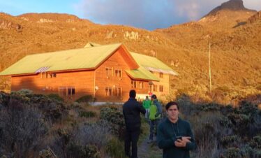 El Cisne mountain refuge surrounded by páramo vegetation in Los Nevados National Natural Park, Colombia, illuminated by golden sunrise light.