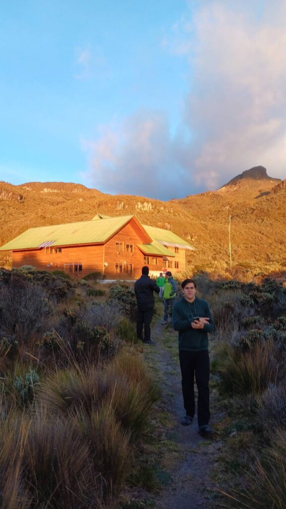 El Cisne mountain refuge surrounded by páramo vegetation in Los Nevados National Natural Park, Colombia, illuminated by golden sunrise light.