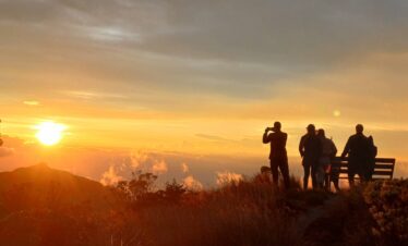 Visitors watching a colorful sunset from El Cisne viewpoint above the clouds in Los Nevados National Natural Park, Colombia.