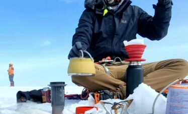 Mountaineer brewing Colombian coffee on the glacier of Nevado Santa Isabel during a high-altitude expedition in the Colombian Andes