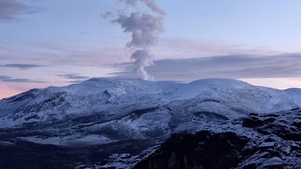 Nevado del Ruiz volcano emitting a steam plume above snow-covered slopes in Los Nevados National Natural Park, Colombia.