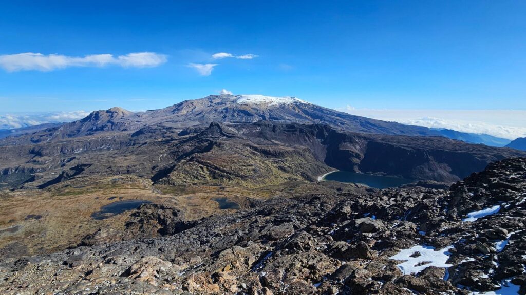Panoramic view of Nevado Santa Isabel, volcanic terrain, and alpine lakes in Los Nevados National Natural Park, Colombia.