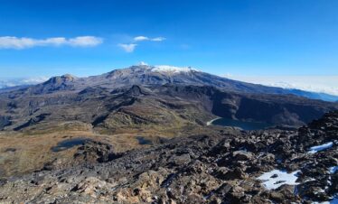 Panoramic view of Nevado Santa Isabel, volcanic terrain, and alpine lakes in Los Nevados National Natural Park, Colombia.