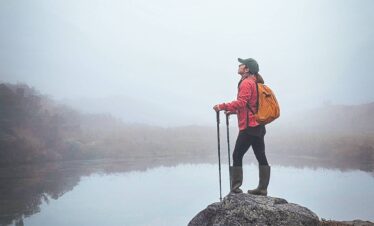 Hiker standing beside a misty high-altitude lagoon in the páramo ecosystem of the Colombian Andes.